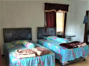 Dos camas una al lado de la otra en una habitación. en Lembah Biru Lagoon, en Mandai