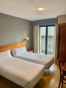 a hotel room with two beds and a window at Hotel Los Templarios in Ponferrada