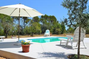 a pool with an umbrella and a table and chairs at Finca Son Bernat 137 by Mallorca Charme in Llubí