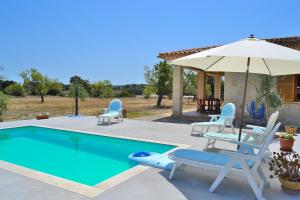 a swimming pool with chairs and an umbrella at Finca Son Bernat 137 by Mallorca Charme in Llubí