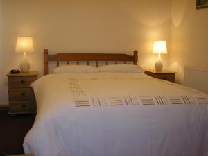 a bedroom with a large white bed with two lamps at Balhousie Farm Bed and Breakfast in Kirkton of Largo