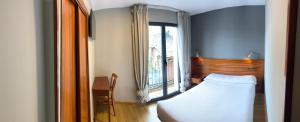a bedroom with a bed and a large window at Hotel Los Templarios in Ponferrada