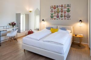 a white bedroom with a white bed and a table at Seehotel Hubertushof in Velden am Wörthersee