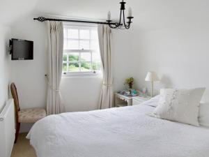 a white bedroom with a bed and a window at Higher Tresmorn Farm in Crackington Haven
