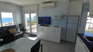 kuchnia z salonem z kanapą i lodówką w obiekcie Apartament Oasis A6 ROSES w mieście Roses