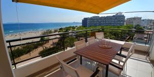 balkon z drewnianym stołem i krzesłami oraz plażą w obiekcie Apartament Oasis A6 ROSES w mieście Roses