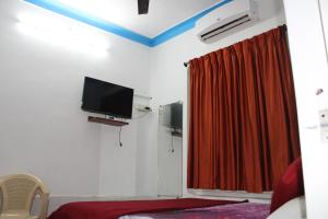 a room with a tv and a red curtain at Balaji Guest House in Puducherry