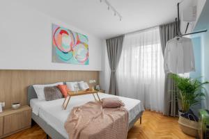 Eden by CityLife Suites في بوخارست: غرفة نوم مع سرير مع طاولة عليه