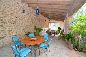 a patio with a wooden table and blue chairs at Finca Son Barraquer 047 by Mallorca Charme in Llubí