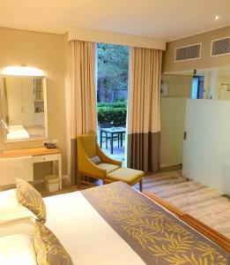 a hotel room with a bed and a chair and a window at Royal St. Andrews Hotel, Spa and Conference Centre in Port Alfred