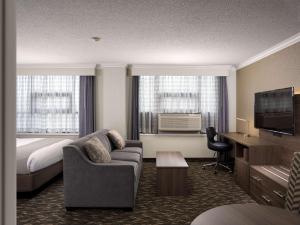 a hotel room with a couch and a bed and a television at BEST WESTERN PLUS Carlton Plaza Hotel in Victoria +21 photos