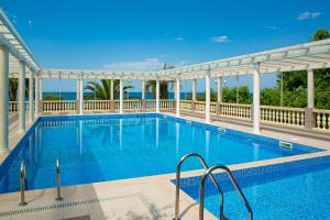 a swimming pool with a white canopy and a resort at Alex Resort & Spa Hotel in Gagra