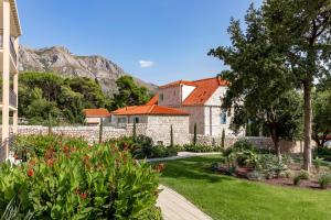 a house with a yard with flowers and a fence at Maistra Select Srebreno Villas in Mlini