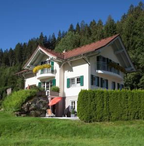 a large white house with green windows and a hedge at Chalet Claudia in Neustift im Stubaital