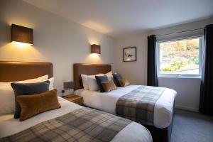 a hotel room with two beds and a window at Harbour House in Ullapool