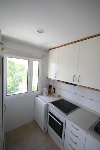 Una cocina con gabinetes blancos y un fregadero y una ventana. en Tamarells 11, en Puerto Pollensa