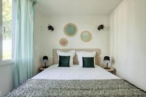 1 dormitorio con 1 cama blanca grande con almohadas verdes en Le Cottage Nature Primeur Sauna Gaillac entre Albi-Toulouse & Les Cottages du Tarn, en Brens