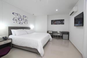 バランキージャにあるHotel Oxford Barranquillaの白いベッドルーム(大型ベッド1台、デスク付)