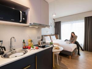 a woman sitting on a bed in a hotel room at Adagio access Brussels Delta in Brussels