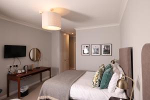 um quarto com uma cama, uma secretária e uma televisão em Michelangelos - Rooms, Restaurant & Bar em Gateshead