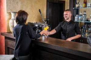 Een vrouw in een bar met een barman. bij Katalina SPA Resort in Tsigov Chark