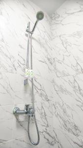 a shower with a shower head on a white marble wall at Белая студия Вокзал Харьков-Пассажирский in Kharkiv +13 photos