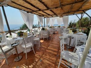 a room with white tables and chairs and the ocean at Villa Donna Antonia - Amalfi Coast in Conca dei Marini