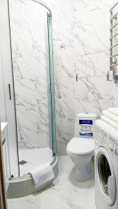a bathroom with a shower and a toilet and a washing machine at Белая студия Вокзал Харьков-Пассажирский in Kharkiv