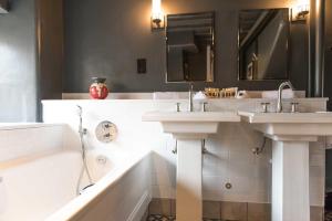 a bathroom with two sinks and a bath tub at The Lygon Arms - an Iconic Luxury Hotel in Broadway