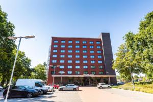 un bâtiment avec des voitures garées dans un parking dans l'établissement Bastion Hotel Tilburg, à Tilbourg