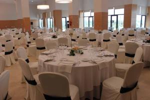 uma sala cheia de mesas e cadeiras com toalhas de mesa brancas em Hospedium Hotel Valles de Gredos Golf em Talayuela