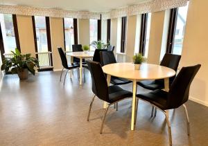 a group of tables and chairs in a room with windows at STF Kalix Vandrarhem in Kalix