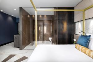 a bedroom with a large white bed and a bathroom at Lure Hotel & Spa - Adults Only in Mellieħa