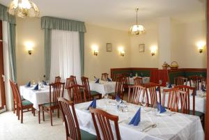 ein Restaurant mit weißen Tischen und Stühlen mit blauen Servietten in der Unterkunft Hotel Kentaur in Siófok
