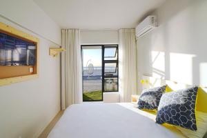 1 dormitorio con 1 cama grande y ventana en Mojo Hotel & Market, en Ciudad del Cabo