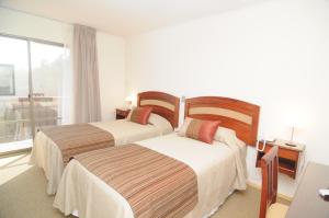 2 camas en una habitación de hotel con ventana en Hotel Ontiveros, en San Fernando