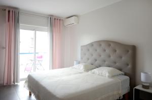 1 dormitorio con cama blanca y ventana grande en 2BDR Reine Astrid en Cannes