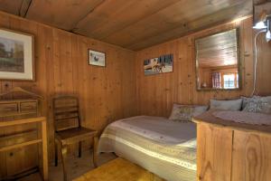 a bedroom with a bed and a chair in a room at B&B La Pivoine in Rossinière