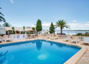 una piscina con tumbonas y el océano en Hotel Lago Dorado - Formentera Break, en La Savina