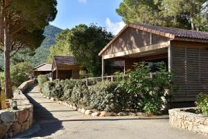 a house with a row of bushes next to a road at Résidence & Hotel U Livanti ECOLABEL in Propriano
