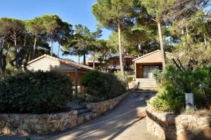 a house with a stone wall next to a driveway at Résidence & Hotel U Livanti ECOLABEL in Propriano