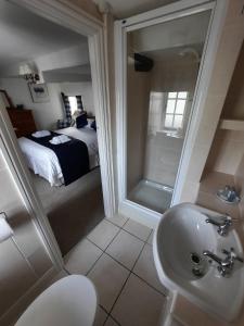 Un baño con lavabo y ducha y una cama. en The White Cottage, en Colyton 32 fotos más