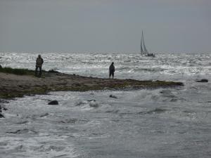 two people standing on a beach near the ocean at Apartementhäuser Marlene & Olivia in Juliusruh