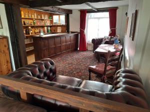 a living room with a leather couch and a bar at The White Cottage in Colyton