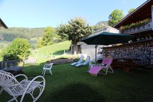 a group of chairs and an umbrella in a yard at B&B La Pivoine in Rossinière
