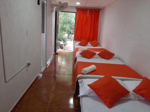 Habitación con 3 camas con almohadas de color naranja. en Hostal Villa Cecilia en Villavieja