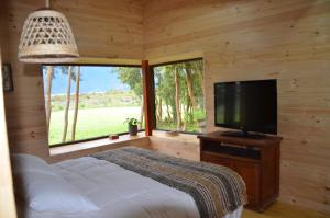 a bedroom with a bed and a flat screen tv at Cabañas Almalik in Ralún