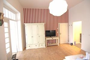 Kapitaenshaus-Lassen-Zimmer-Kapitaen-Blaubaer في فيسترلاند: غرفة معيشة مع تلفزيون بشاشة مسطحة وغرفة مع جهاز تلفاز