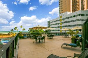 un patio avec des tables et des parasols et l'océan dans l'établissement Transamerica Prestige Recife - Boa Viagem, à Récife