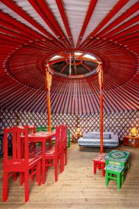 a red tent with a table and chairs in it at Le Village Insolite yourte et roulotte in Saint-Benoît-des-Ondes